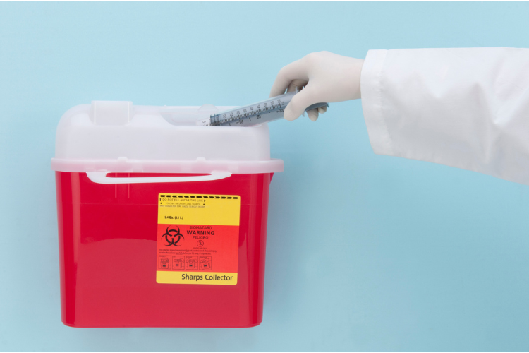 hand disposing of medical waste in an approved container