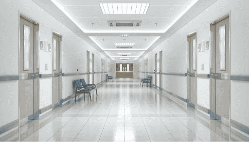 An empty hospital hallway with white walls and tiled floor.