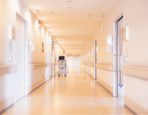 An empty hospital hallway that is well-lit and tan in color.