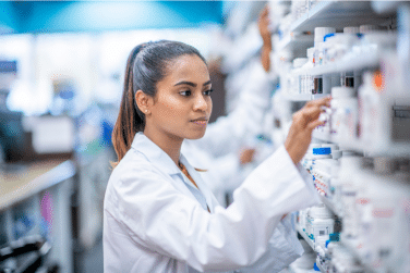 Pharmacist looking at rows of drugs