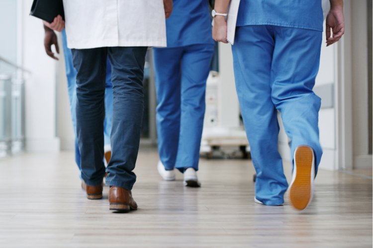 How often should healthcare organizations assess their compliance programs is known by these medical workers walking confidently down a hallway