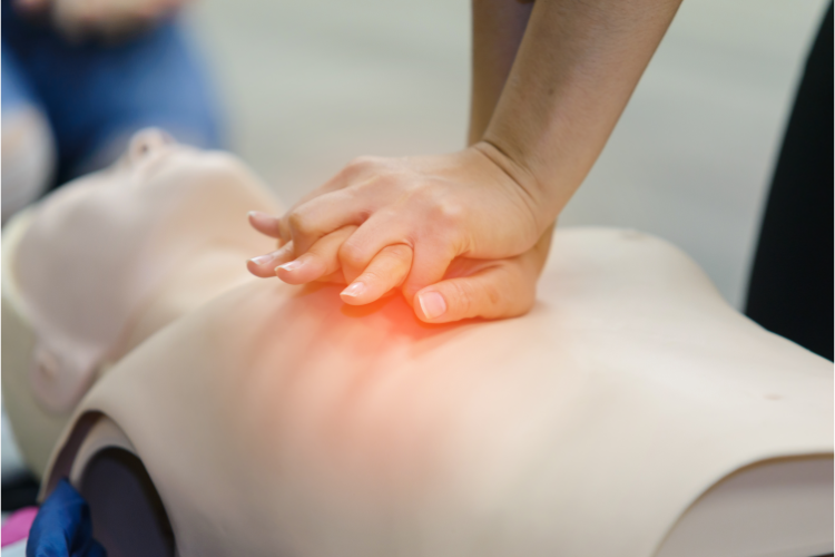 Hands performing CPR on a training dummy
