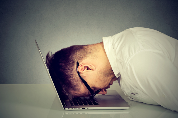man with his head down on laptop in frustration