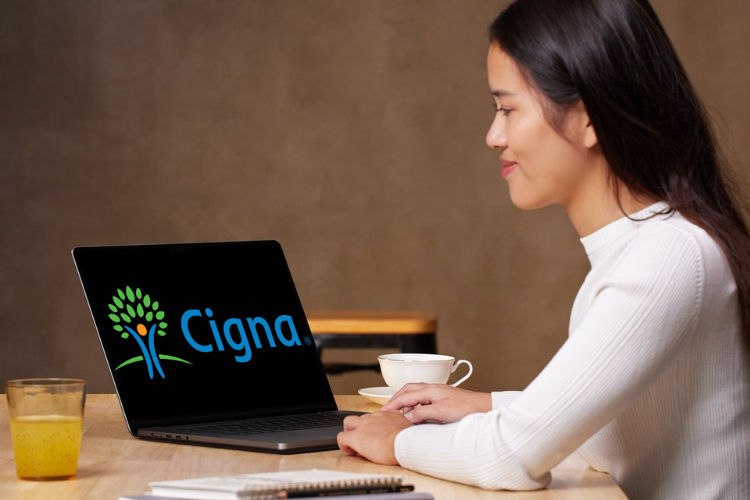 Woman sitting at a computer with Cigna logo on the screen
