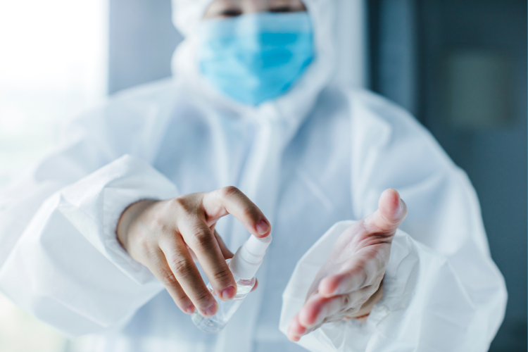 A healthcare professional spray sanitizer on hands