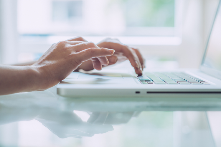 Person's hands typing on laptop keyboard