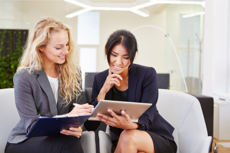 Two professionals sitting and looking at a tablet